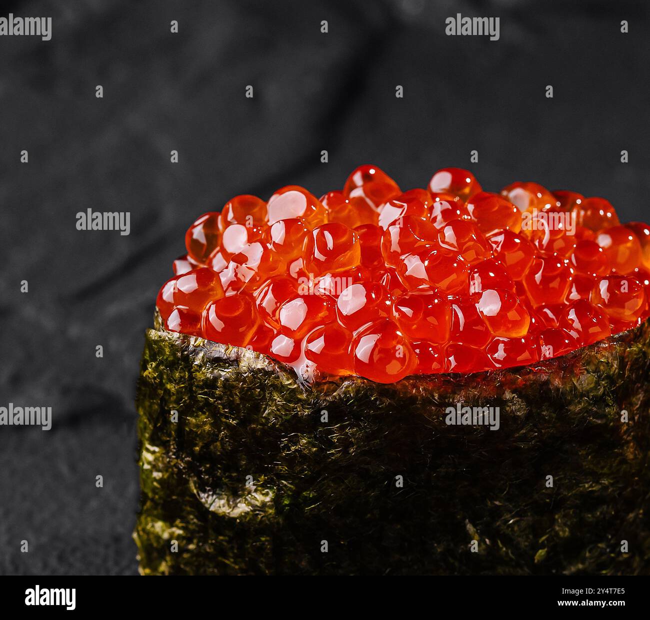 Einzelnes Stück Lachsrogen Sushi elegant auf einem strukturierten dunklen Schieferhintergrund angeordnet Stockfoto