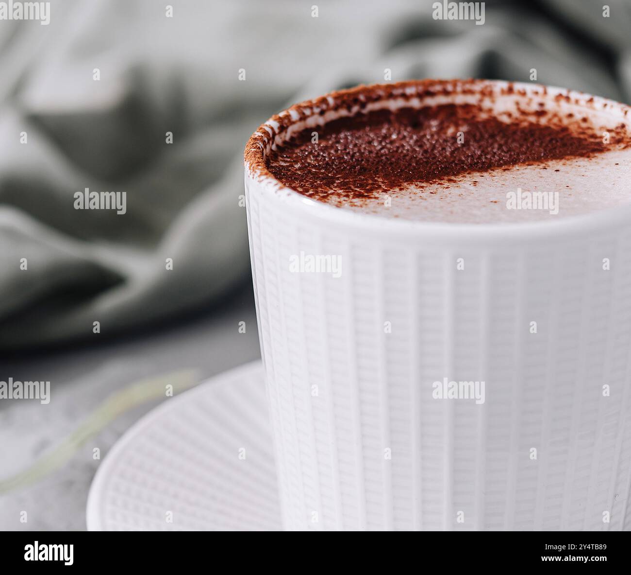 Gemütliche Szene mit einer weißen Tasse Cappuccino mit Schaumkunst und Grün Stockfoto