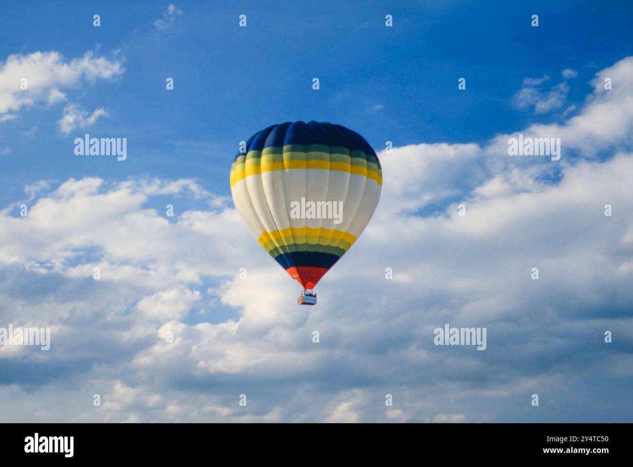 Montgolfière naviguant dans un ciel nuageux et bleu Stockfoto