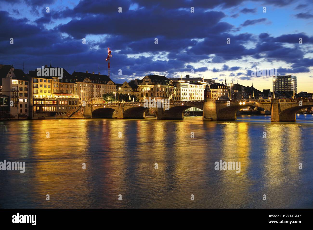 Abendlicher Stadtblick auf Basel mit beleuchteter Brücke und reflektierenden Lichtern im Wasser, Mittelrheinbrücke, Basel, Schweiz, Europa Stockfoto