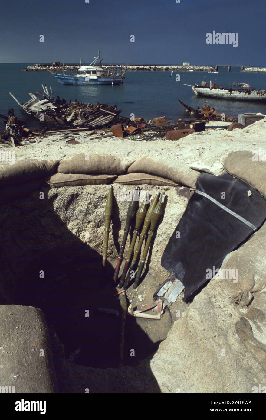 8. März 1991 RPG-7 Munition, sowjetische 85-mm-PG-7-Raketen/Granaten, in einem verlassenen irakischen Bunker in Kuwait City. Im Hintergrund liegt ein Teil der zerstörten Dhow-Flotte Kuwaits im Old Ships Port. Die hölzernen Fischerboote sind Kuwaits nationales Symbol. Stockfoto