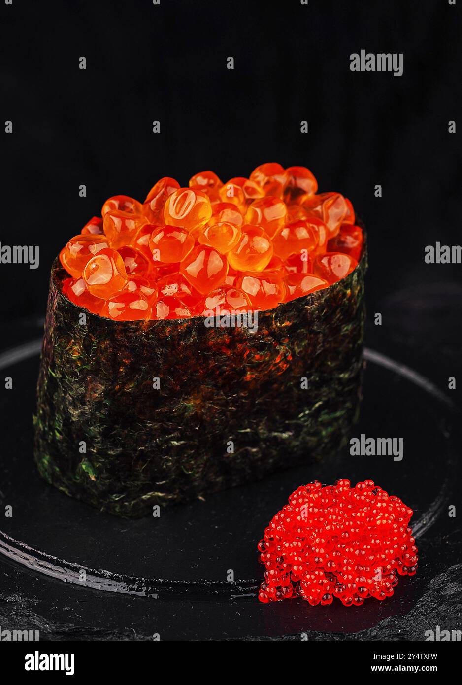 Gunkan Maki Sushi mit tobiko fliegenden Fischrogen wird auf einem schwarzen Steinteller serviert Stockfoto