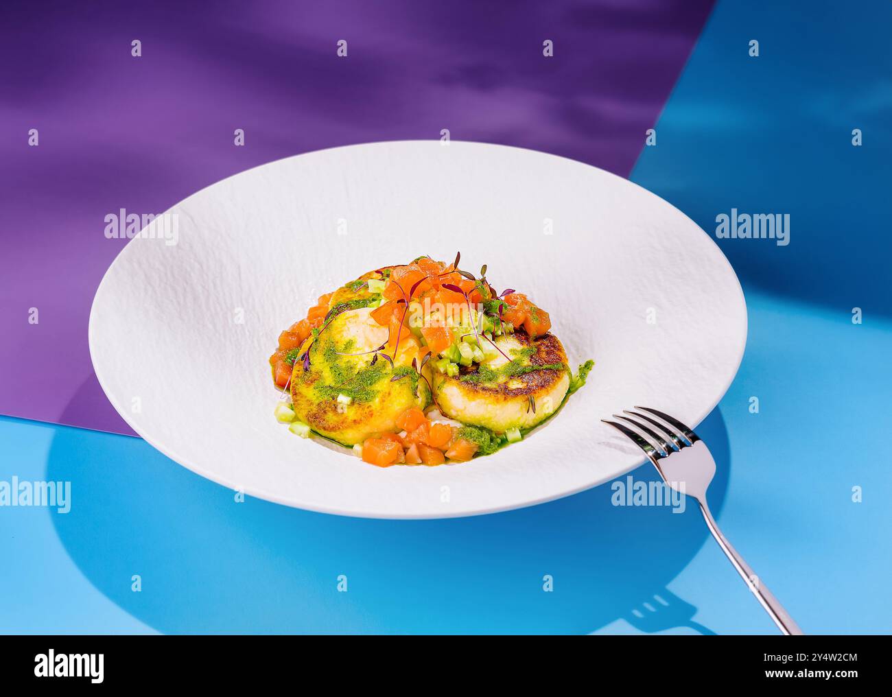 Lachstartar mit Avocado und Zucchini-Pfannkuchen, elegant auf einem weißen Designer-Teller angeordnet, schaffen ein optisch ansprechendes kulinarisches Erlebnis Stockfoto