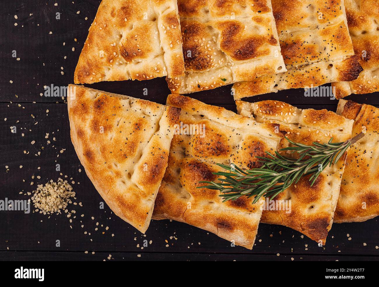 Türkisches ramadan-Pide-Brot wird auf einem dunklen Holztisch mit Sesam und Rosmarin serviert Stockfoto