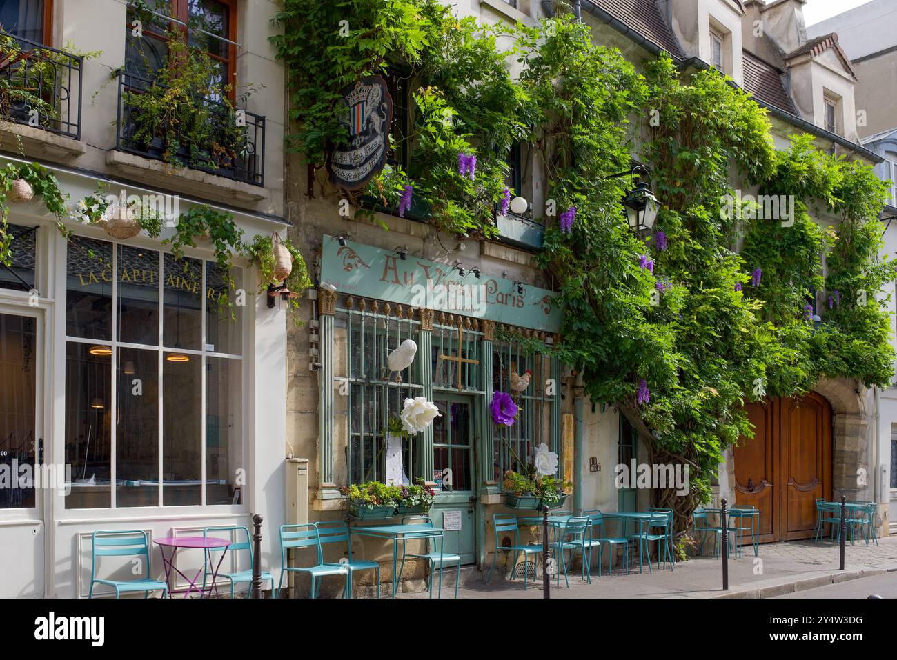 Charmantes ältestes Restaurant mit Außenterrasse mit farbenfrohen Tischstühlen im Herzen von Paris Stockfoto