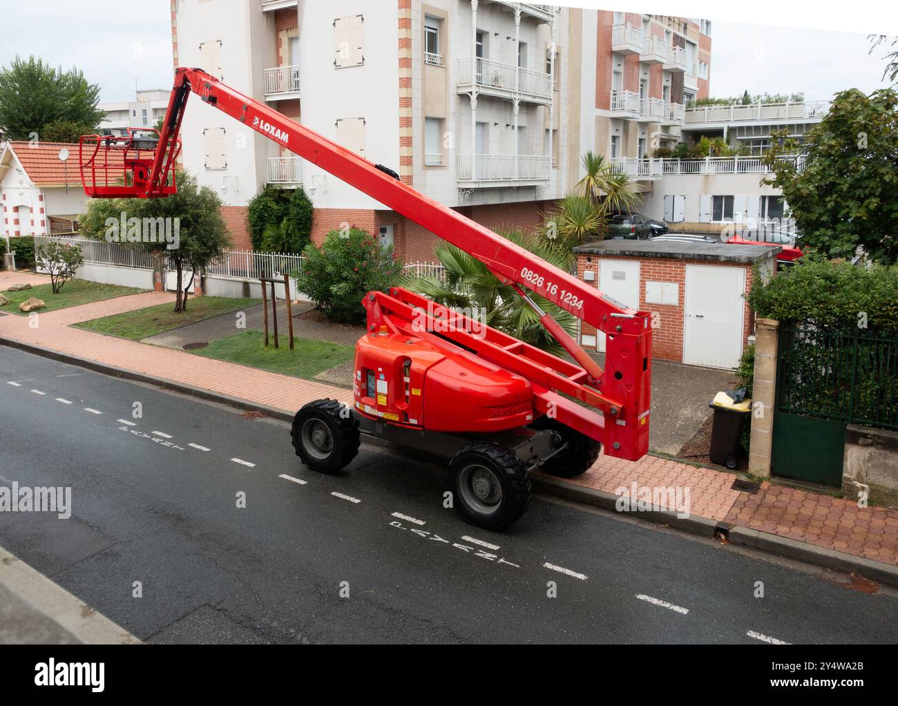 Ein hellroter Haulotte Cherry Picker Lift steht auf einer Wohnstraße. Stockfoto