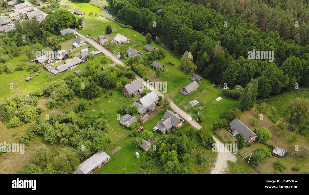 Blick aus der Vogelperspektive auf ein kleines Dorf mit traditionellen Holzhäusern, umgeben von üppig grünen Wäldern und einem sich windenden Fluss Stockfoto
