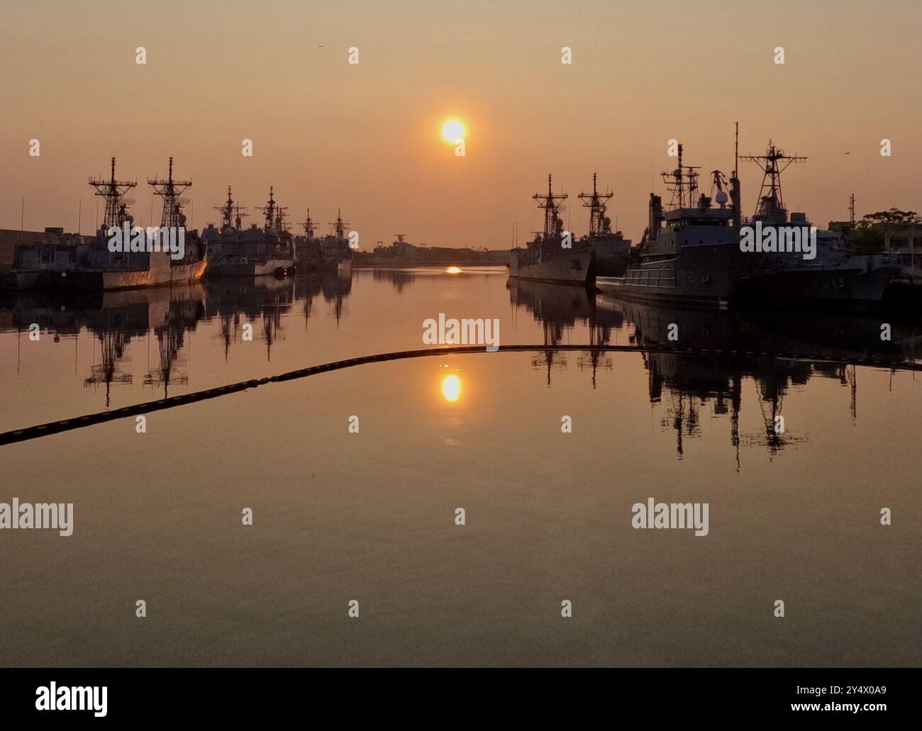 Schiffe im Becken der Naval Inactive Ship Maintenance Facility (NISMF) in Philadelphias Navy Yard sind bei Sonnenaufgang mit Silhouetten versehen. Stockfoto