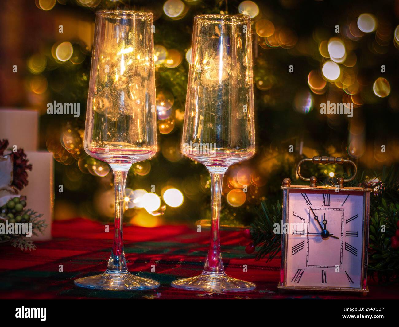 Zwei toastende Sektgläser und Countdown-Uhr auf glitzerndem Hintergrund, frohe Neujahrsfeier Stockfoto