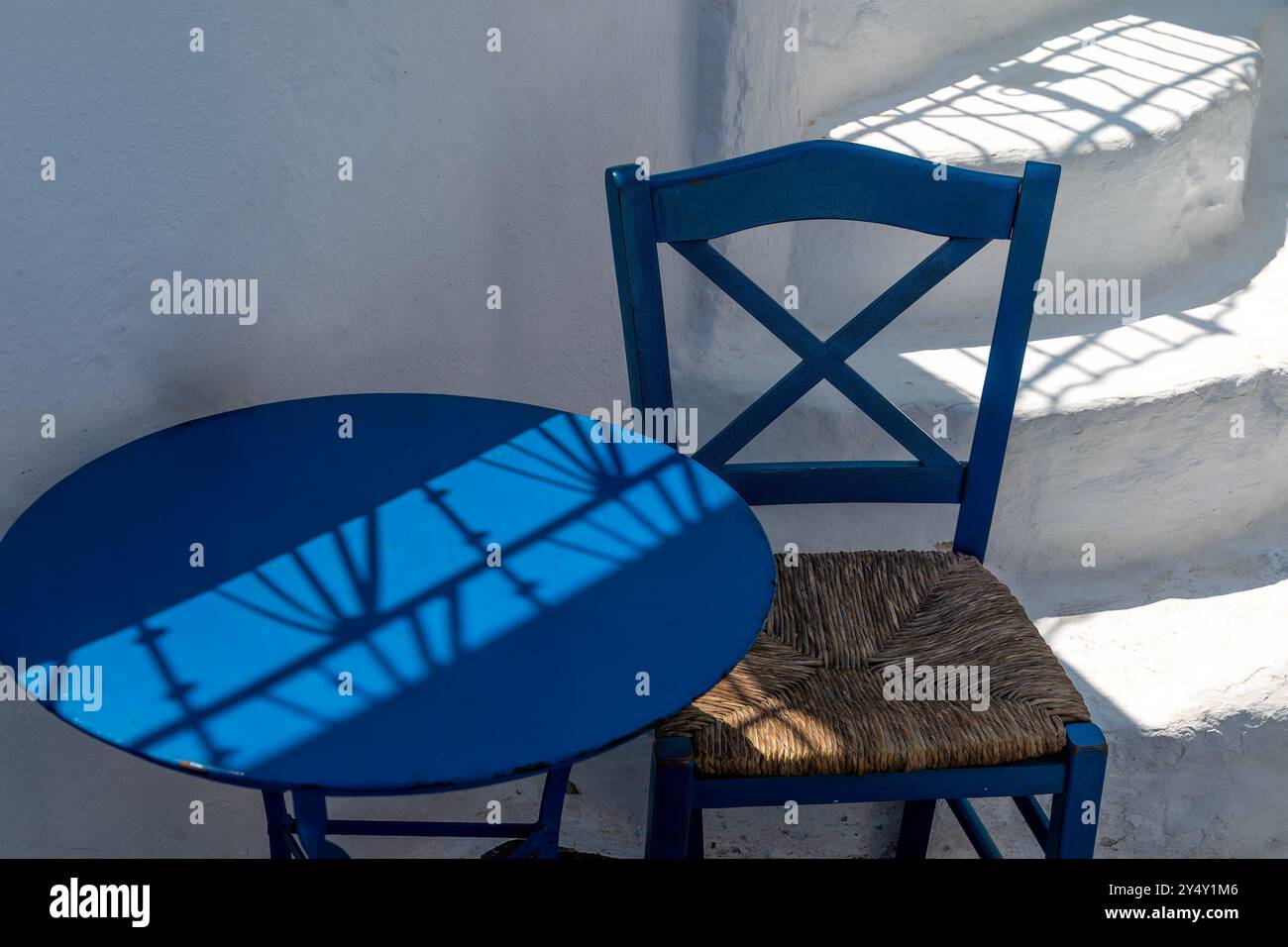 Farben, Formen, Schatten. Traditioneller blau lackierter Stuhl, Tisch, weiß getünchte Treppe. Formen aus Megalochori, Santorin, Griechenland Stockfoto