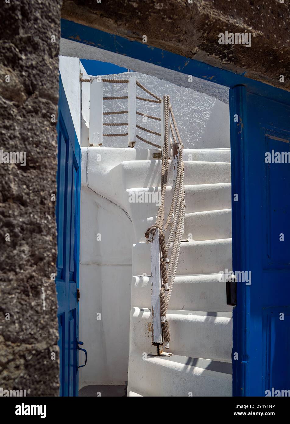 Abstrakt weiß getünchte Wände, blaue Tür, Stufen und Winkel in Megalochori, Santorin, Griechenland. Stockfoto