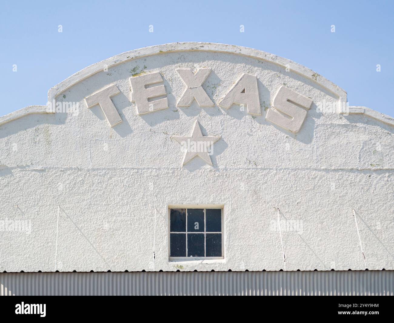 Die Fassade eines weißen Gebäudes, das in bogenförmigen Buchstaben Texas steht und einen Stern und ein Fenster hat. Stockfoto