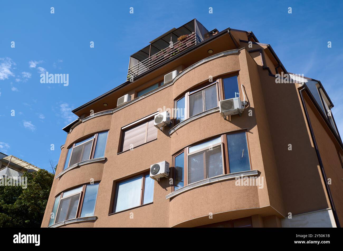 Modernes architektonisches Design eines mehrstöckigen Gebäudes mit geschwungenen Linien und weitläufigen Fenstern unter einem klaren blauen Himmel Stockfoto