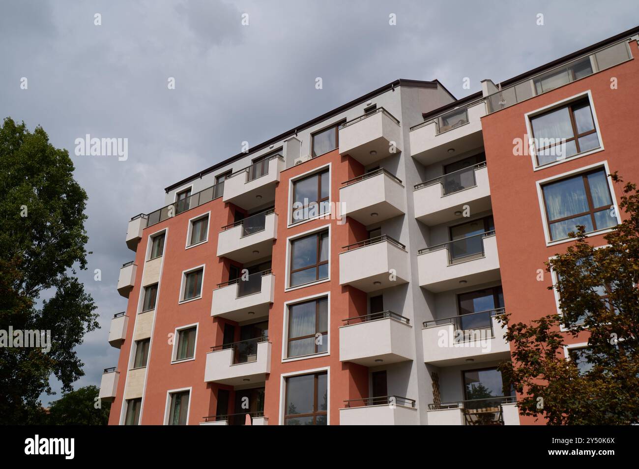 Modernes Mehrfamilienwohngebäude mit zeitgenössischer Architektur in einer urbanen Umgebung unter teilweise bewölktem Himmel Stockfoto