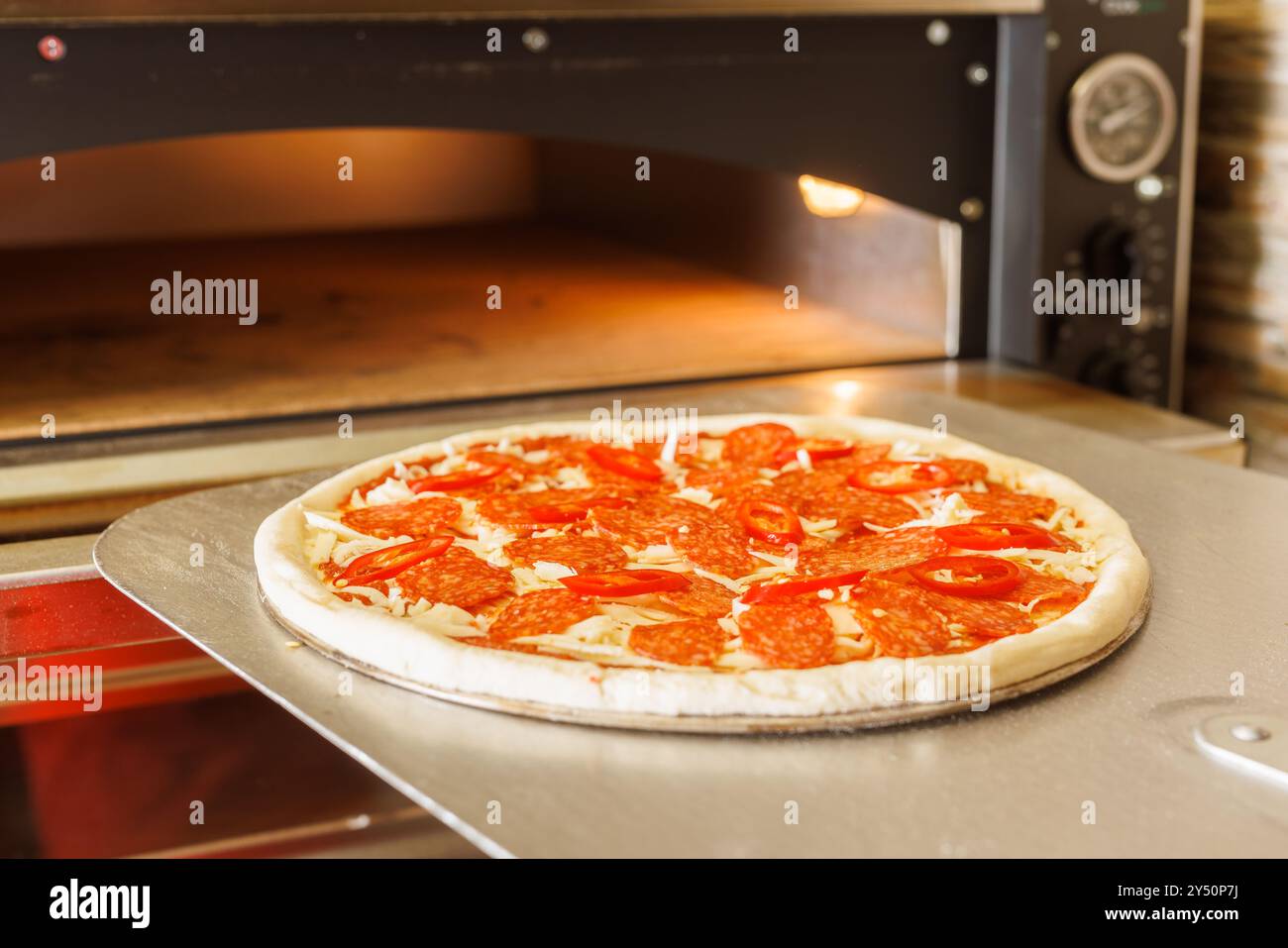 Eine frisch gebackene Pizza, die aus einem Pizzaofen mit einer Pizzaschale genommen wird. Stockfoto