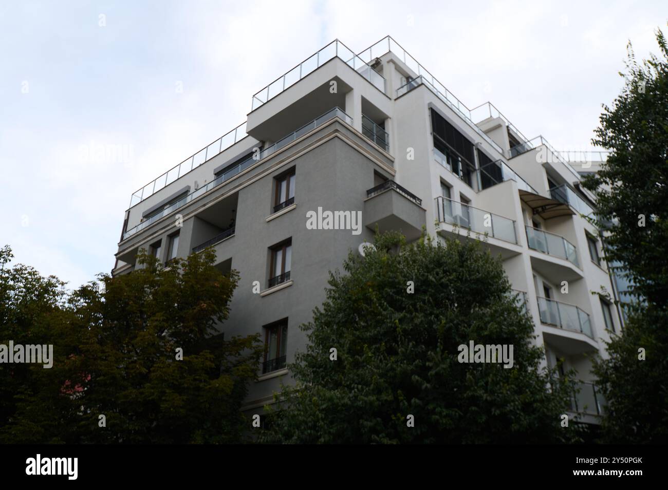 Modernes Wohngebäude mit Balkonen und Grün in städtischer Umgebung an einem bewölkten Tag Stockfoto