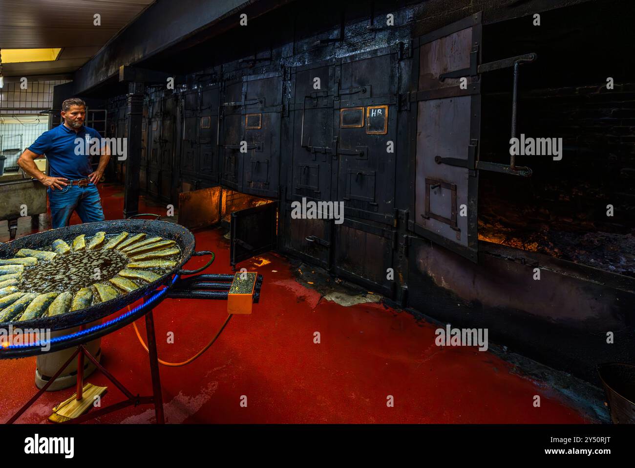 Matthias Föh, Besitzer der Fischräucherei Föh in vierter Generation, vor den drei Rauchöfen. Die auf Buchen- und Erlenholz geräucherten Öfen stammen aus den 1920er Jahren und sind durch drei ikonische Ziegelsteine miteinander verbunden. Das Fischrauchhaus Föh mit seinen drei Türmen ist ein Wahrzeichen von KappelnDehnthof, Kappeln, Schleswig-Holstein, Deutschland Stockfoto