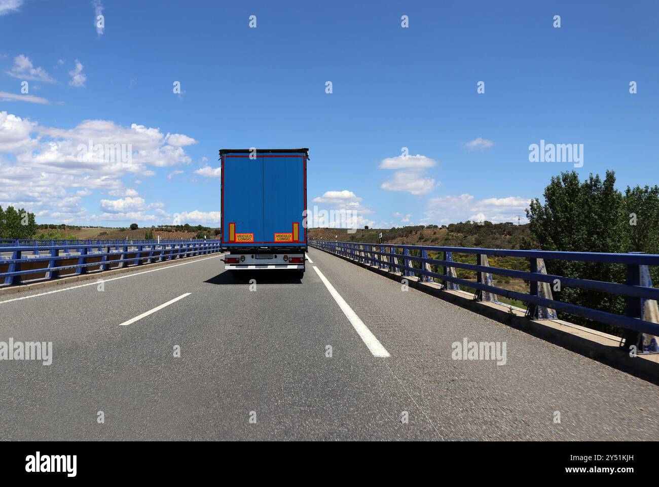 Blauer Lastwagen auf der Autobahn gegen blauen Himmel an einem sonnigen Tag Stockfoto