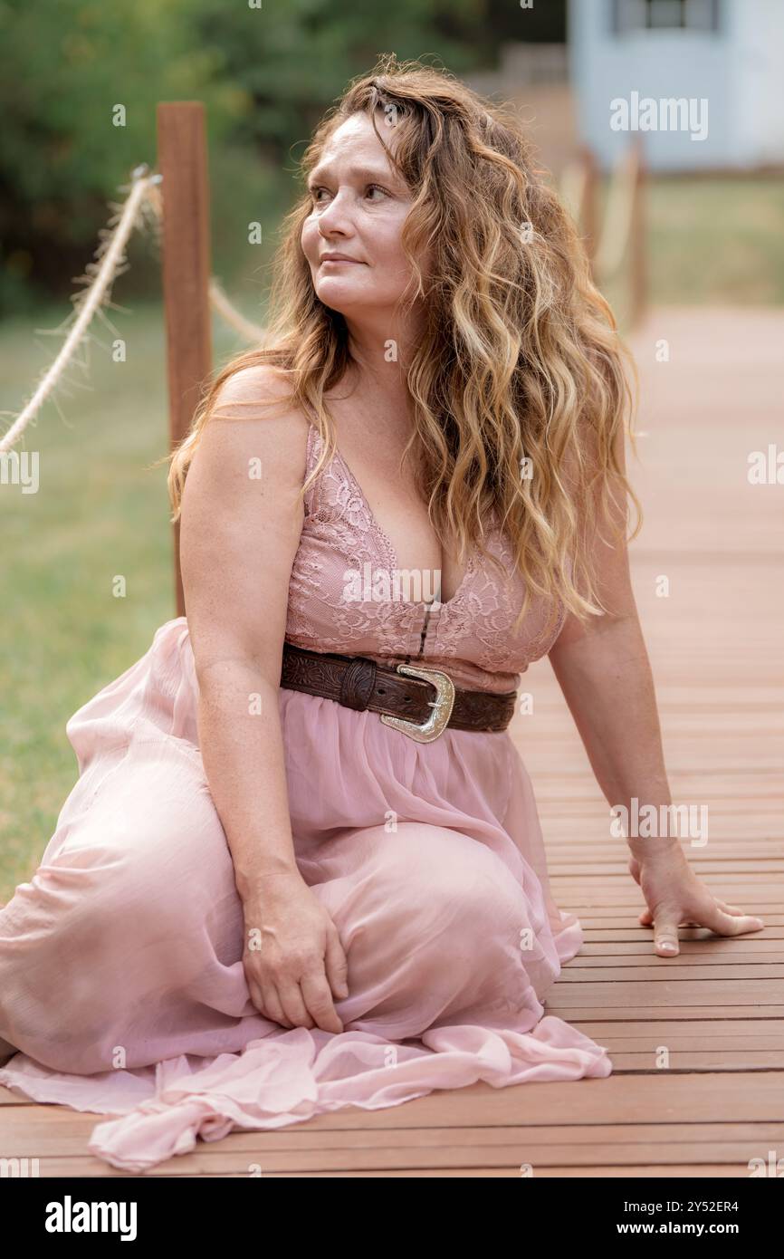 Dame mit gewelltem Haar sitzt auf dem Dock Stockfoto
