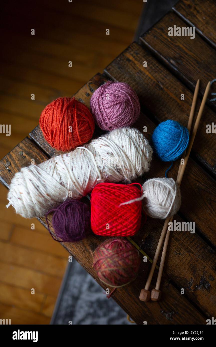 Bunte Garnbällchen und Stricknadeln auf Holztisch Stockfoto