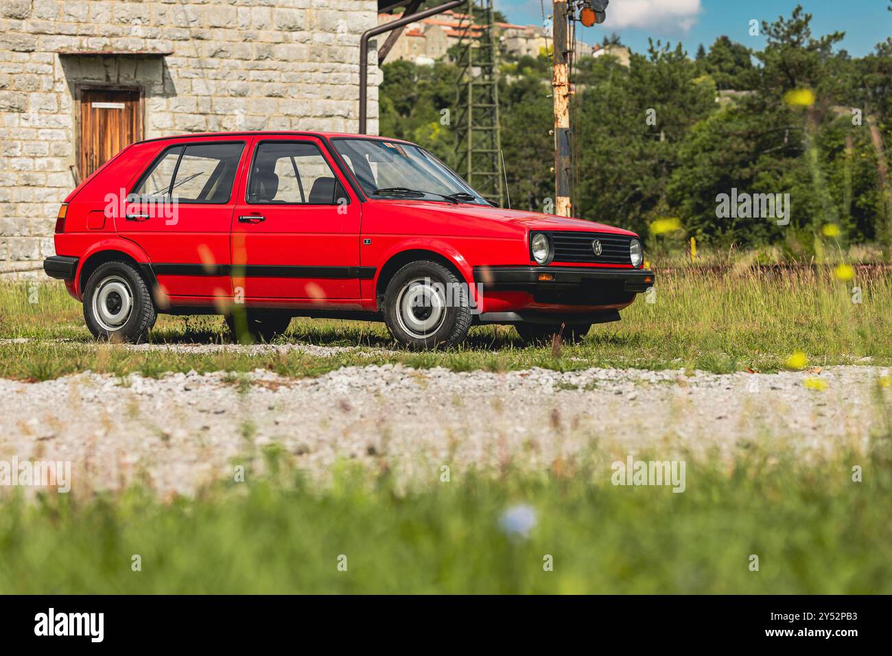 Stanjel, Slowenien, 19.9,2024: Alter Volkswagen Golf in roter Farbe und 5 Türen, 1,6D Diesel posiert auf einer Station vor einem majestätischen Stanjel Dorf Stockfoto