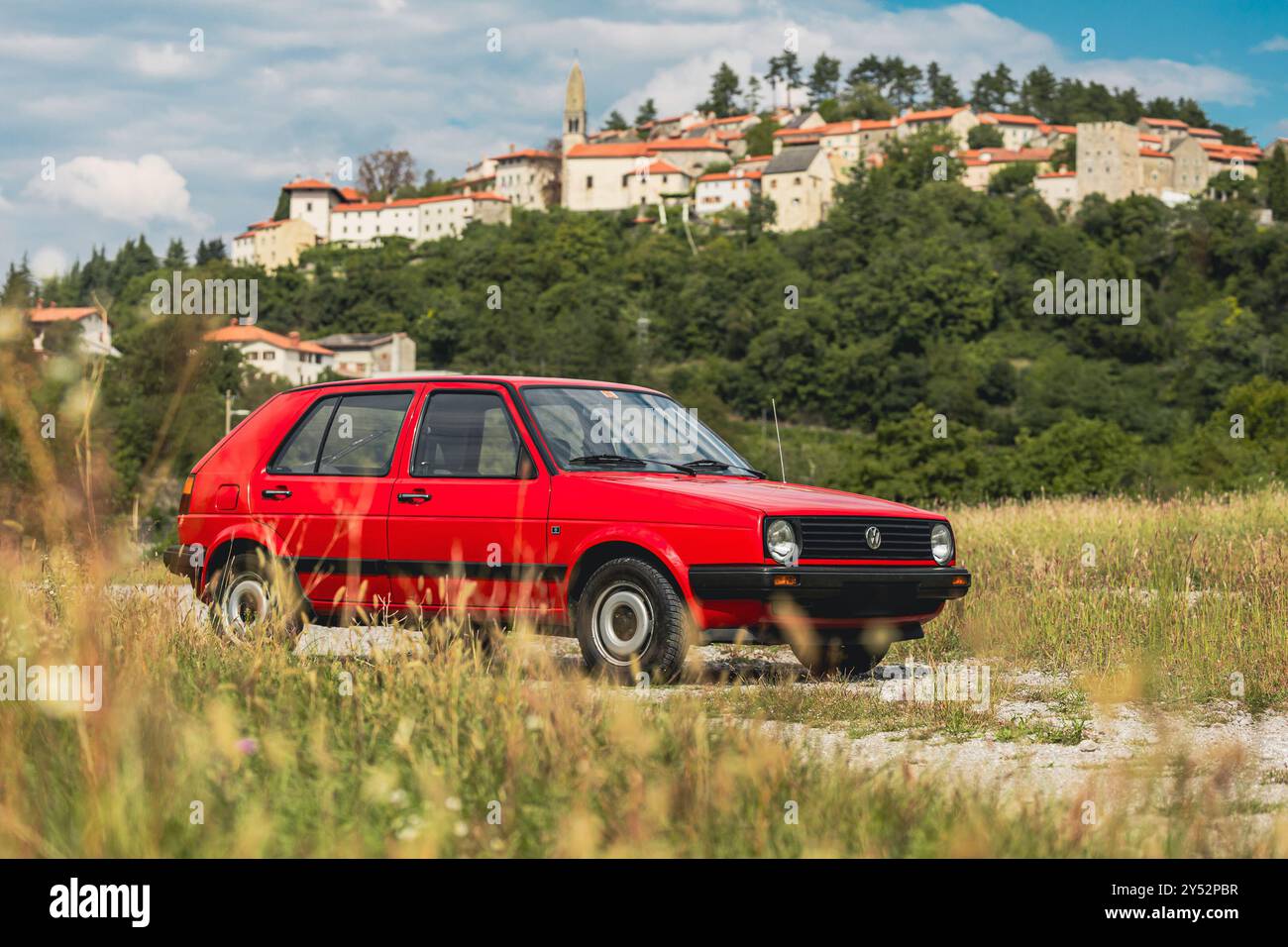 Stanjel, Slowenien, 19.9,2024: Alter Volkswagen Golf in roter Farbe und 5 Türen, 1,6D Diesel posiert auf einer Station vor einem majestätischen Stanjel Dorf Stockfoto