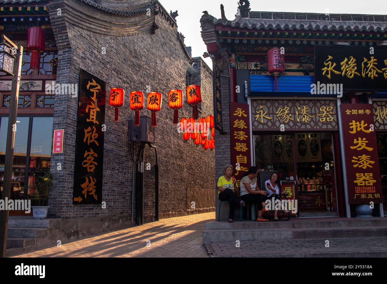 Gasse in Ping Yao, Shanxi, China. Die untergehende Sonne beleuchtet die roten Laternen. Stockfoto