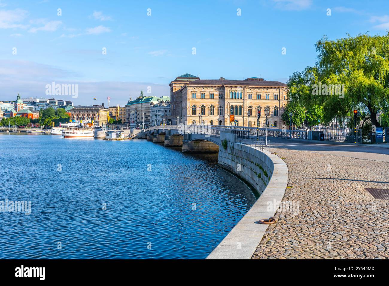 Die Skeppsholmen-Brücke erstreckt sich über das Wasser mit dem schwedischen Nationalmuseum an einem hellen sonnigen Tag im Hintergrund. Stockholm, Schweden Stockfoto