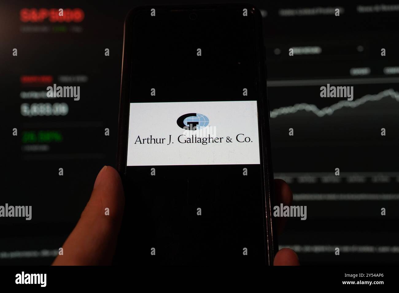 In dieser Fotoabbildung wird das Arthur J. Gallagher & Co.-Logo auf einem Smartphone mit Hintergrund einer S&P-Index-Website angezeigt. Stockfoto