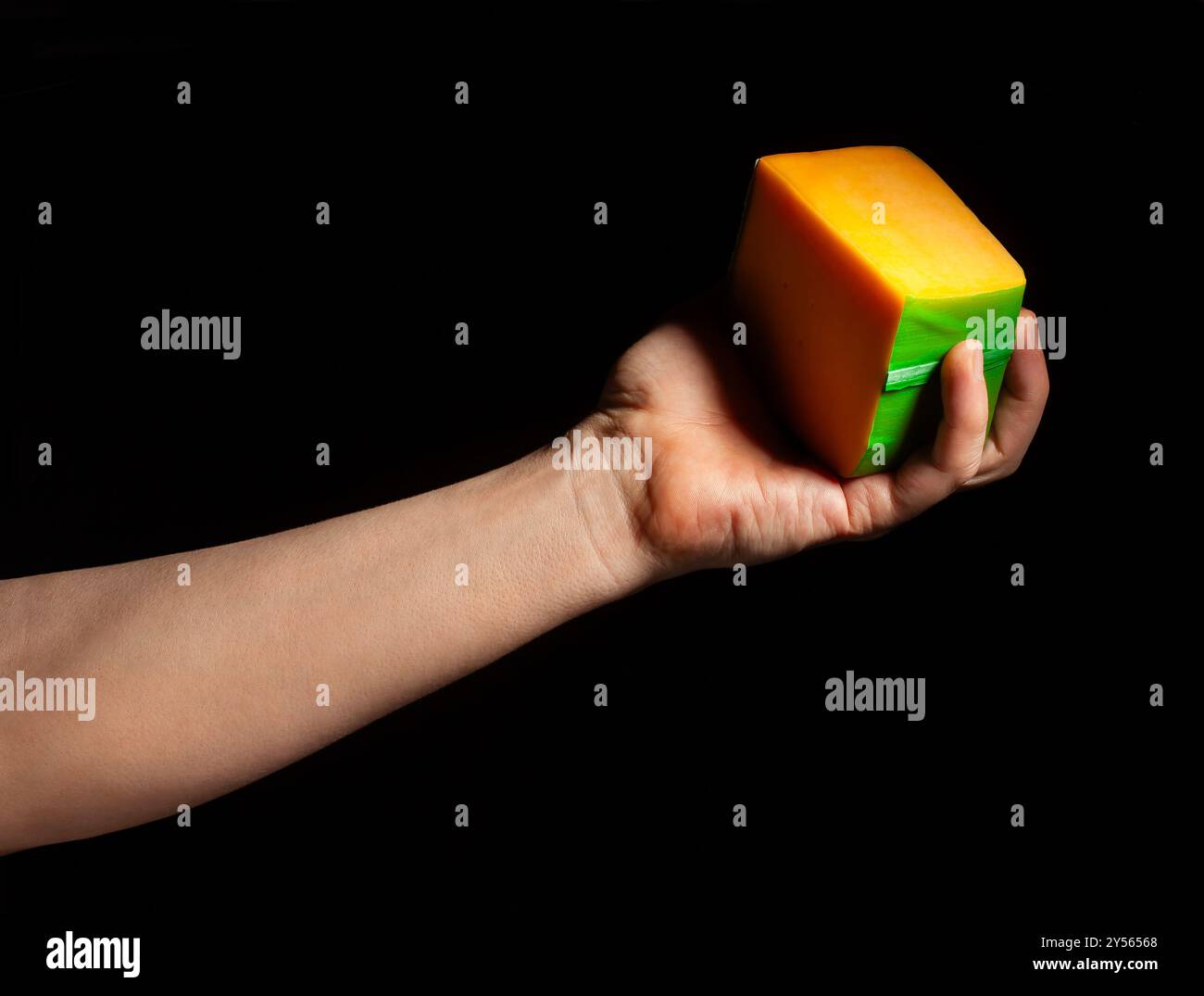 Käse in der Hand auf schwarzem Hintergrund Stockfoto