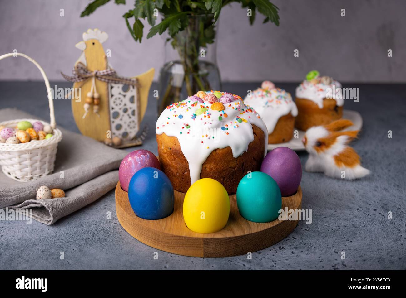 Osterkulich mit kandierten Früchten in weißer Glasur mit bunten Streuseln und bemalten Eiern. Traditionelles Ostergebäck. Osterferien. Nahaufnahme, wählen Sie Stockfoto