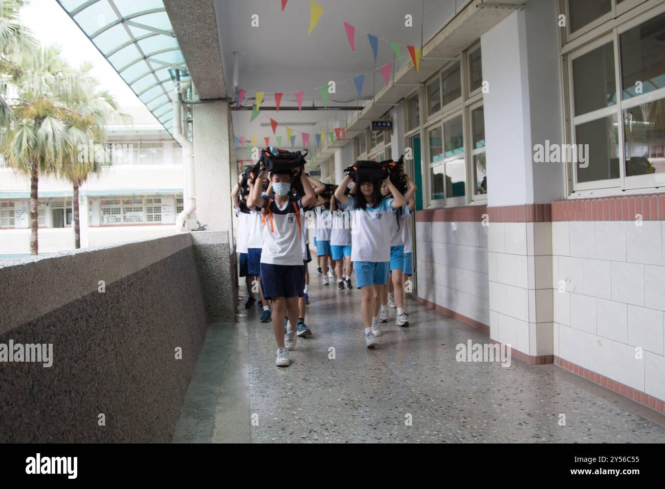 Schüler der Junior High School legten ihre Schultaschen auf den Kopf und gingen nach draußen, um an der jährlichen Erdbebenbohrung in Taipeh im September teilzunehmen Stockfoto
