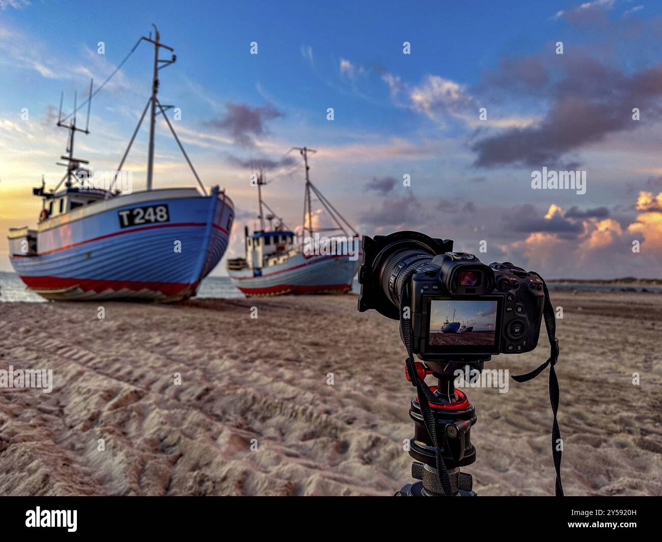 Stativ mit Kamera vor Fischerbooten am Strand in Vorupor, Dänemark, Europa Stockfoto