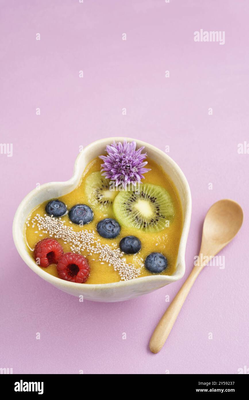 Peach smoothie Schüssel mit Blaubeeren, Kiwi, weiße Chia Samen und Himbeeren in Herzform Schüssel Stockfoto