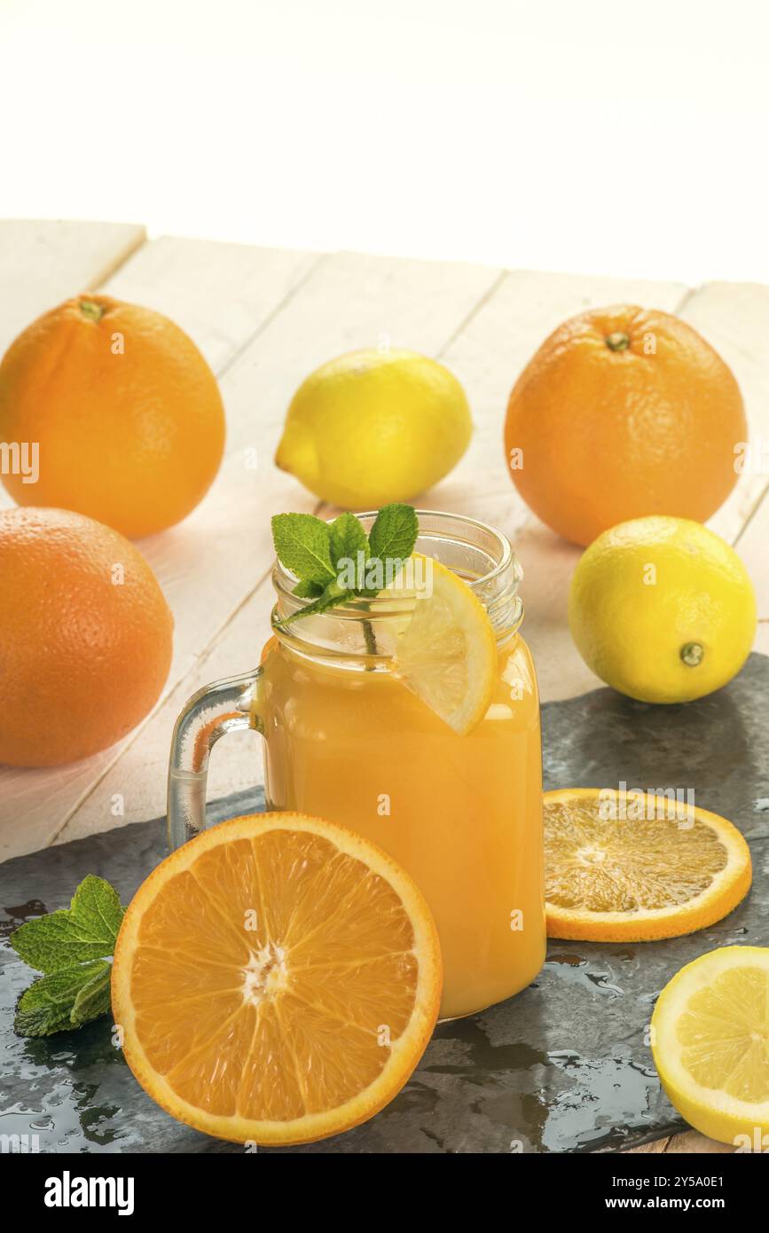 Frisch gepresster Orangensaft in einem Glas, von Orangen und Zitronen Scheiben in einem warmen Sommer Licht umgeben Stockfoto
