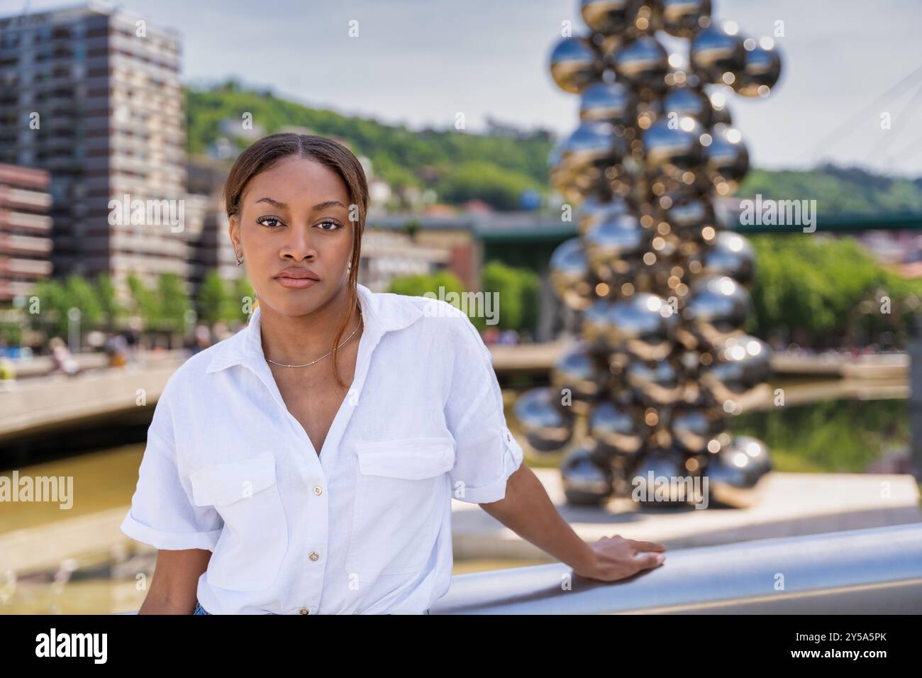 Junge Frau posiert in bilbao mit einer Welpenskulptur von jeff koons im Hintergrund Stockfoto