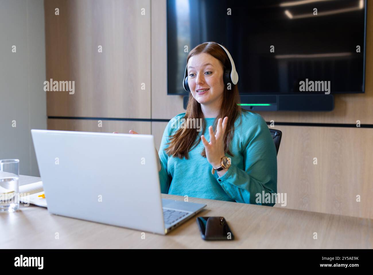 Videogespräche führen, Frau mit Headset mit Laptop im modernen Büro Stockfoto