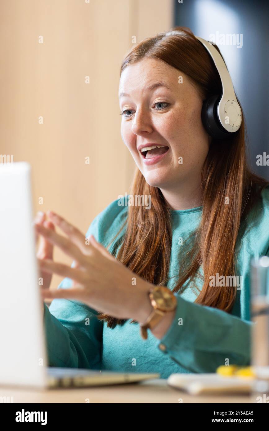 Im Büro, mit Kopfhörern, mit Videoanruf auf einem Laptop, mit Fernarbeit Stockfoto