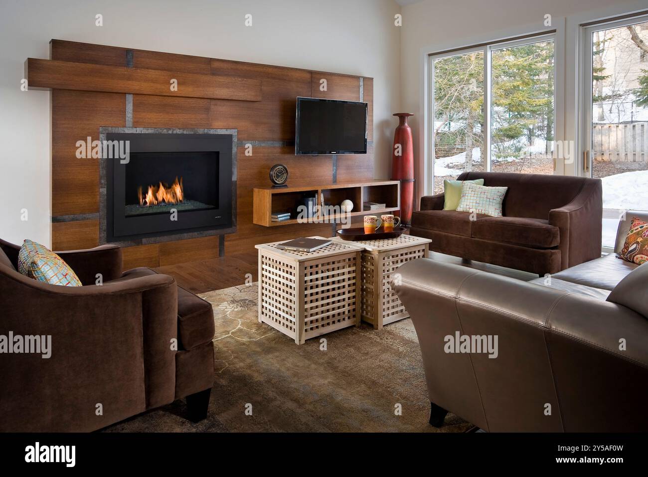 Modernes Familienzimmer mit individuell angefertigtem, modernem Kamin, Fernseher und Regalfach Stockfoto