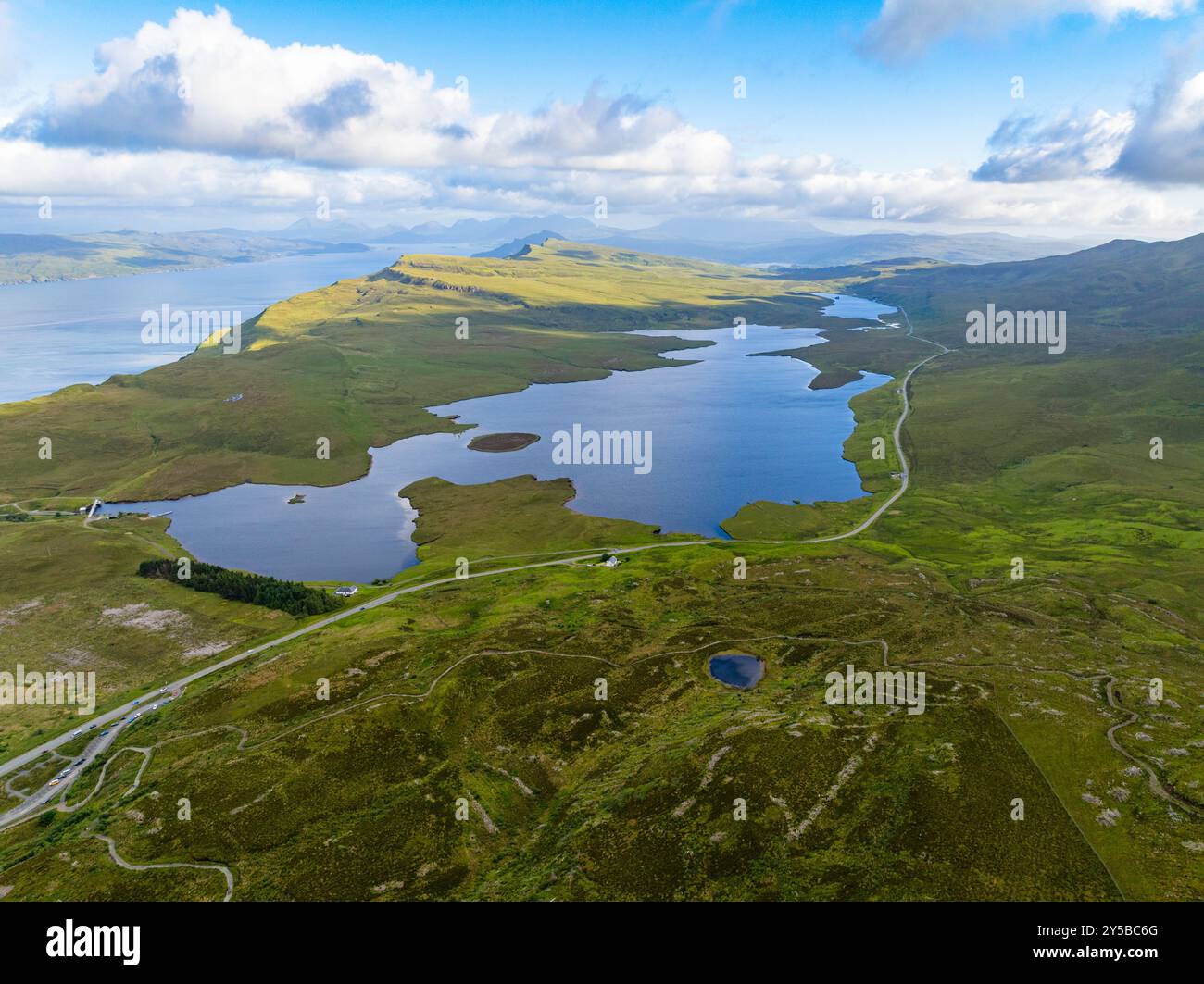 Die landschaftlich reizvolle Route an der Nordküste 500 schlängelt sich um einen See in den schottischen Highlands in der Nähe von Old man of Storr auf der Isle of Skye, Schottland Stockfoto