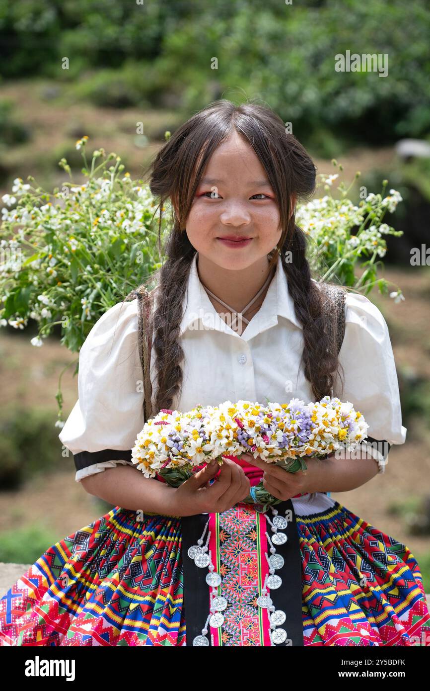 Das lokale Hmong-Mädchen verkauft Blumen entlang der Ha Giang Loop in den Bergen Nordvietnams Stockfoto