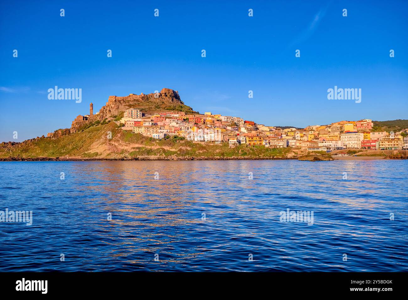 Häuser in der kleinen Küstenstadt Castelsardo, die von der Burg Doria dominiert wird, die den Hafeneingang überblickt. Stockfoto