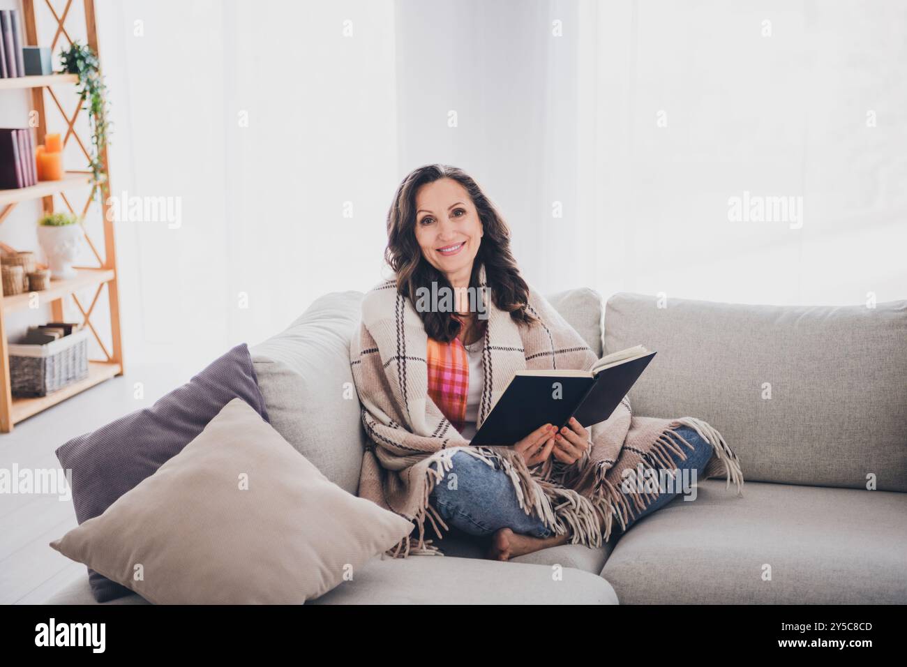 Foto von positiver guter Laune Frau gekleidetes Hemd, das Buch im Wohnraum des Hauses genießt Stockfoto