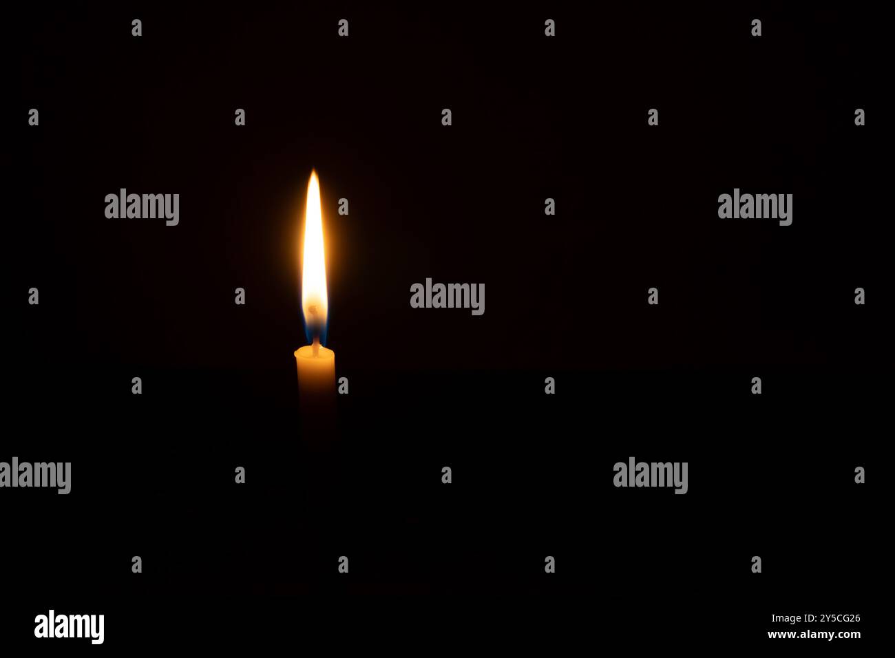 Eine einzelne brennende Kerzenflamme oder Licht leuchtet auf einer kleinen orangen Kerze auf schwarzem oder dunklem Hintergrund auf dem Tisch in der Kirche zu Weihnachten, Beerdigung oder mir Stockfoto