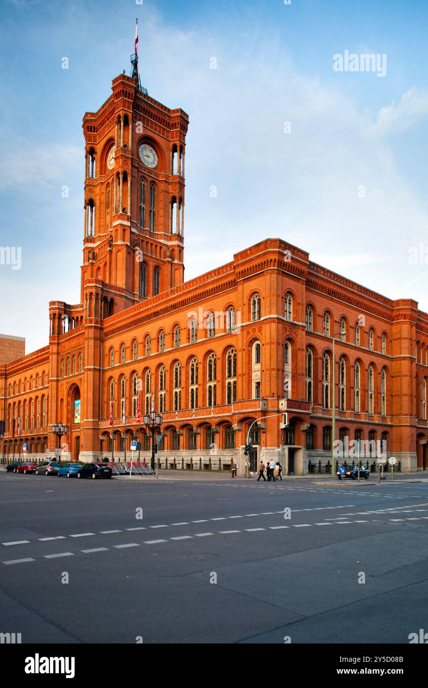 Das berühmte Rote Rathaus steht majestätisch in Berlin und zeigt seine markante rote Fassade, während die Menschen am Abend vorbeischlendern. Stockfoto