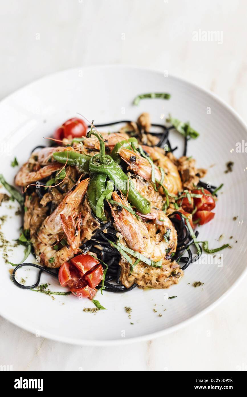 Gourmet-Essen gegrillte Garnelen und Gemüse auf Pasta-Mahlzeit mit schwarzer Tintenfisch-Tinte Stockfoto