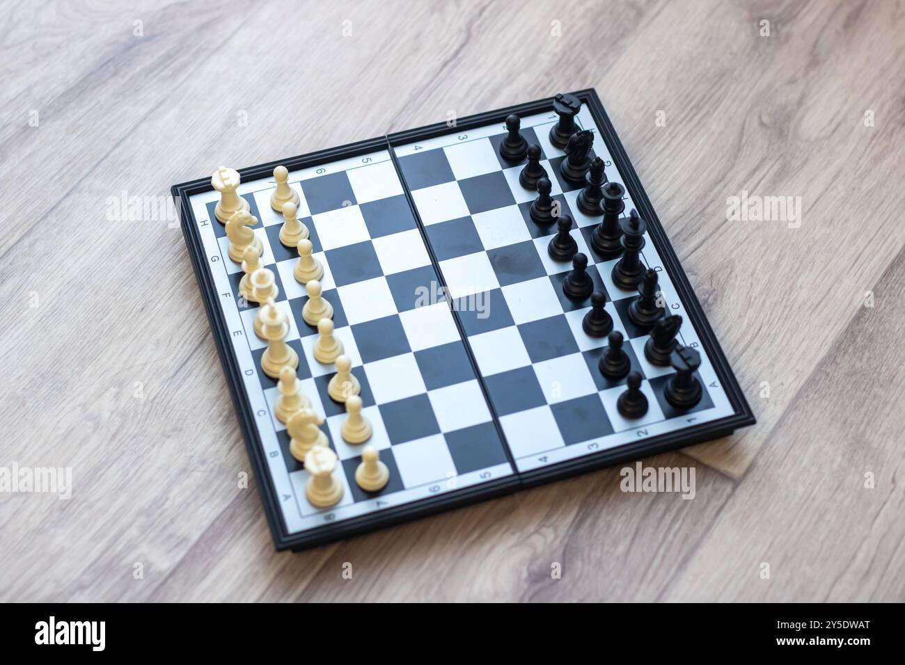 Ein klassisches Schachbrett mit weißen und schwarzen Teilen, die strategisch darauf platziert sind, bereit für ein spannendes Strategiespiel Stockfoto