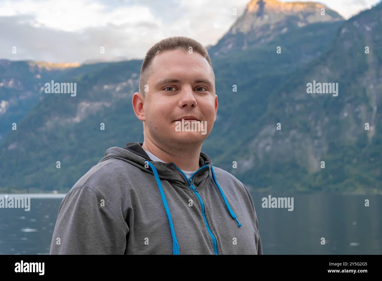 Ein 25-30-jähriger Mann steht an einem hölzernen Pier in der Nähe eines ruhigen Bergsees. Stockfoto