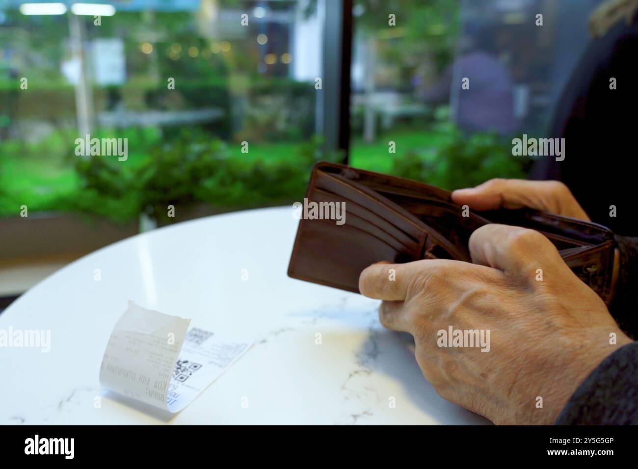 Die Hände des Seniorenmannes, der den Auftragsbeleg und die Brieftasche hält Stockfoto