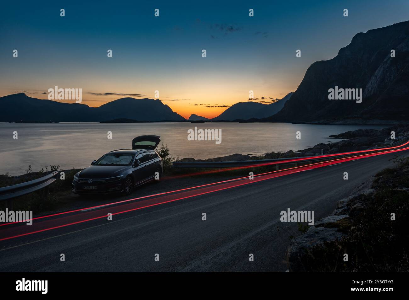 Autoparken Übernachtung während warmer Sonnenuntergang nördlicher Nacht am felsigen Strand mit Bergen und Ampelpfaden, Lofoten Norwegen Stockfoto